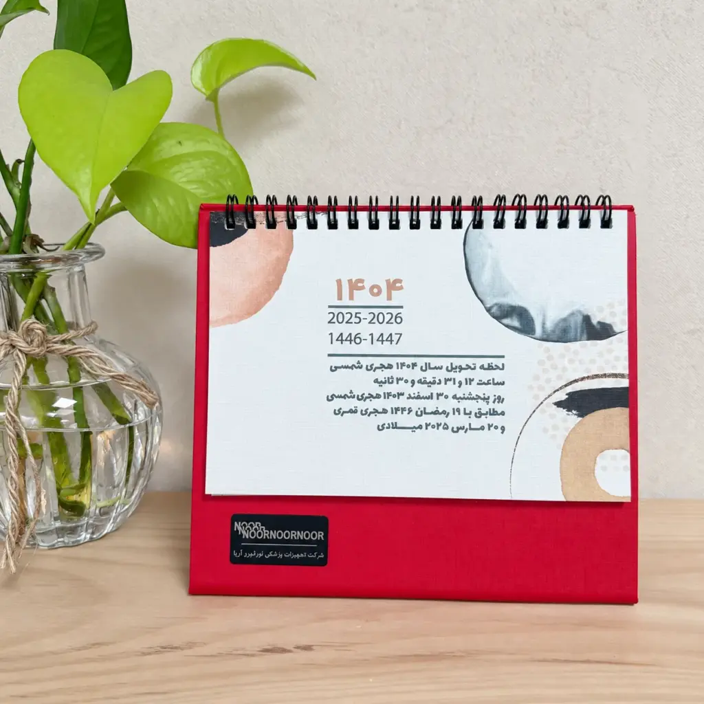 نمونه‌کار تقویم رومیزی قرمز با پلاک لوگوی NOOR